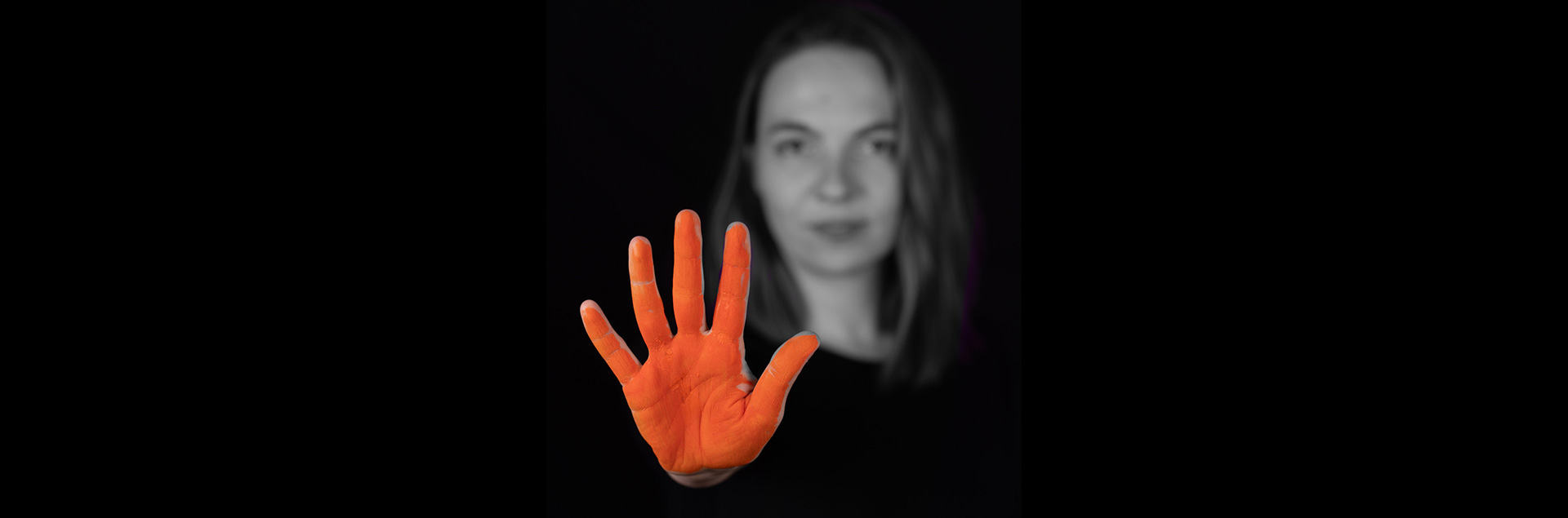Stoppt Gewalt gegen FLINTA* Das Bild zeigt eine FLINTA*-Person. Im Vordergrund steht ihre rot angemalte Hand, die ausgespreizt „Stopp!” bedeutet.